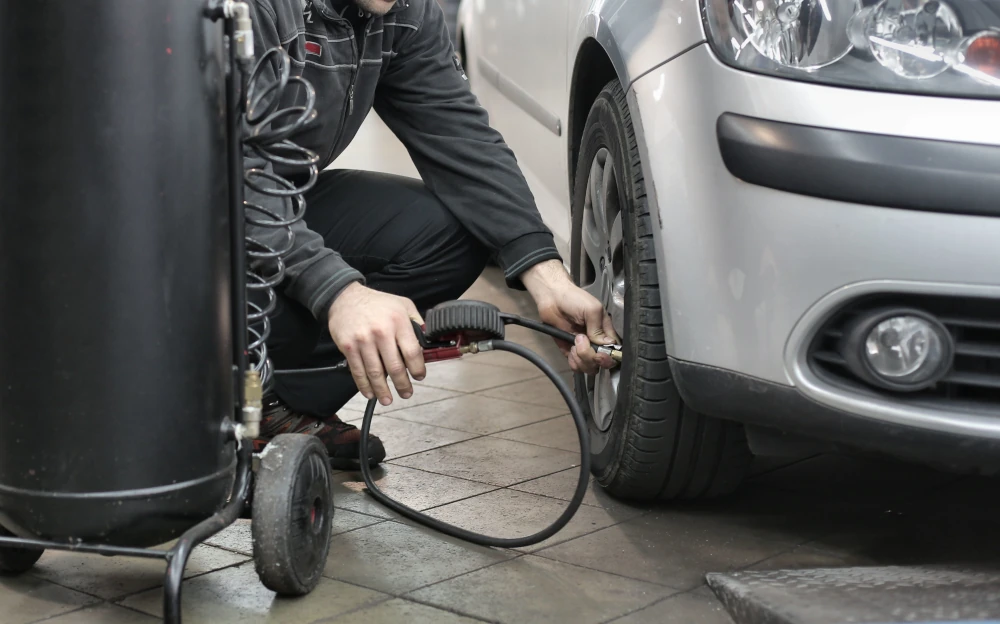 Pessoa calibrando o pneu do carro no posto de combustível